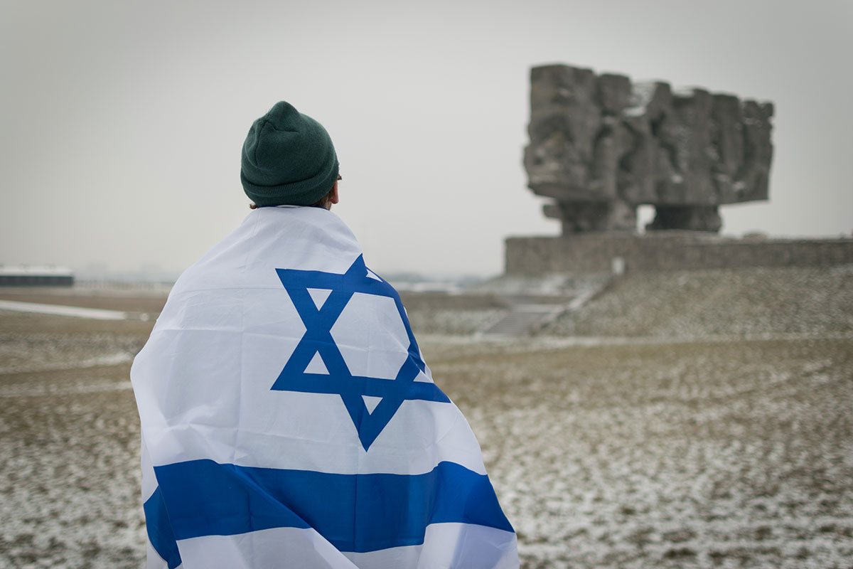 A traveler wrapped in an Israeli flag looking toward a historic site